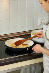 Woman frying pancakes, food, preparing,woman shef, housewife, kitchen, indor, middle half