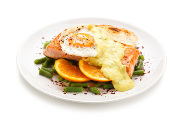 Grilled salmon with sauce, fried egg and vegetables on white background 