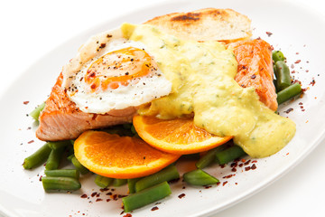 Grilled salmon with sauce, fried egg and vegetables on white background 
