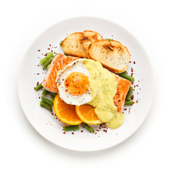 Grilled salmon with sauce, fried egg and vegetables on white background 