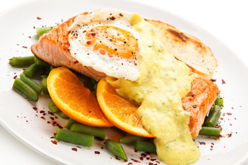 Grilled salmon with sauce, fried egg and vegetables on white background 