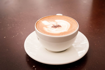  beautiful latte art with cup of hot cappuccino coffee on wooden table.