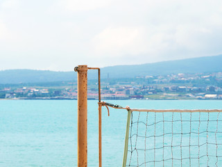 Beach volleyball background. Stretched grid for playing against the background of water, city and mountains