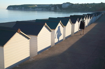 Shadows of people passing by beach huts in Seaton, Devon