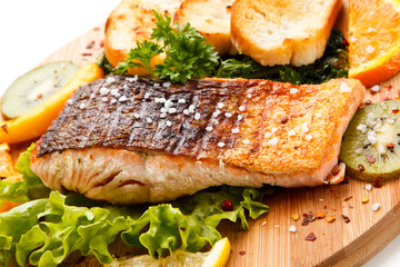 Grilled salmon with bread on wooden board on white background 