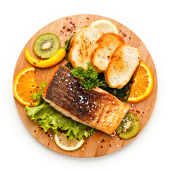 Grilled salmon with bread on wooden board on white background 