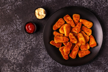Chicken nuggets with sauces on dark background.