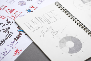 Fototapeta premium Creative sketch in spiral notepad with laptop on desk. Business starup plan.