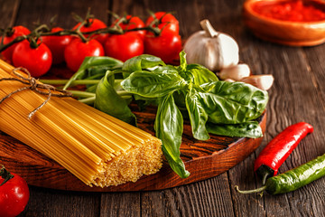 Products for cooking - pasta, tomatoes, garlic, pepper, and basil.