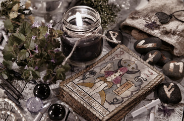 Toned still life with black candle, runes and the tarot cards