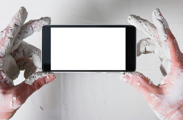 Worker hands in white plaster with smartphone take photo of stucco wall, flat lay. Unrecognizable...