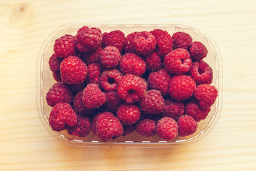 Top view of ripe raspberries in plastic container box