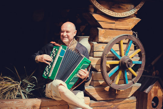 Mature man plays on a musical instrument accordion , is dressed in an embroidered shirt. Unification of the  Slavs on abroad