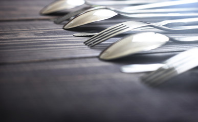 Steel spoons and forks in a row on a table.