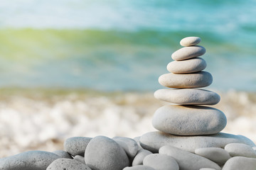 Fototapeta na wymiar Stack of white pebbles stone against blue sea background for spa, balance, meditation and zen theme.