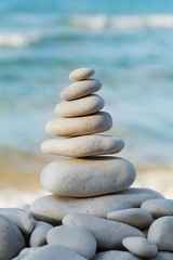Fototapeta na wymiar Stack of white pebbles stone against sea for spa, balance, meditation and zen theme.