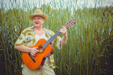 Mature funny  american man  on vacation resting in Mexico playing guitar singing songs, having fun...
