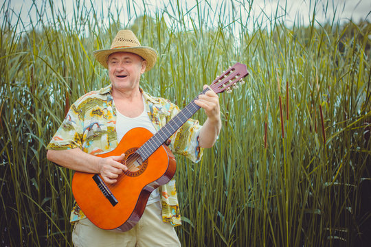 Mature funny  american man  on vacation resting in Mexico playing guitar singing songs, having fun from the heart