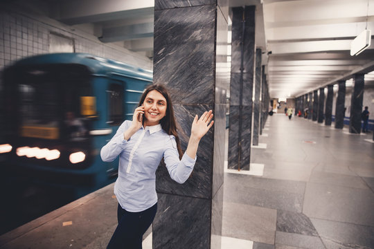 young tourist girl is talking on the phone in the subway and welcomes her hand. The concept is always in touch.