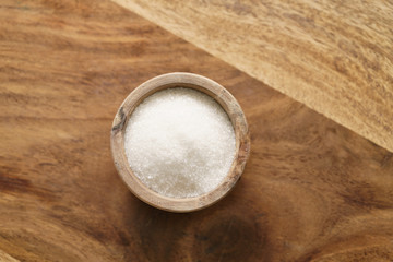 sugar in wood bowl on wooden table from above