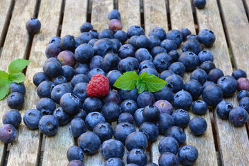 Raspberries, blue berries and black berries on a wooden garden table