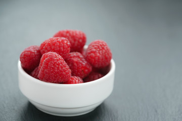 fresh raspberries in white bowl on slate board