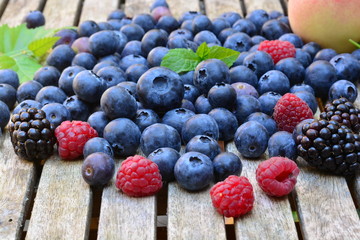 Peaches, raspberries, blue berries and black berries on a wooden garden table