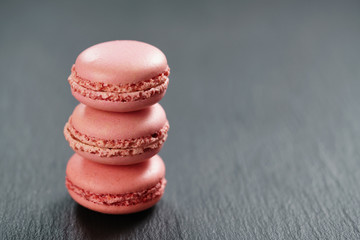raspberry red macarons stacked on slate board