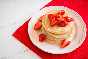 Pancakes with strawberry on a white wooden table. Top view. Selective focus.