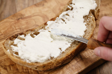 spreading ricotta cheese on fresh rustic bread