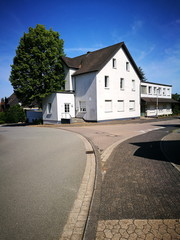 Abzweigung in eine verkehrsberuhigte Zone mit abgesenktem Bordstein in einem Wohngebiet vor blauem...