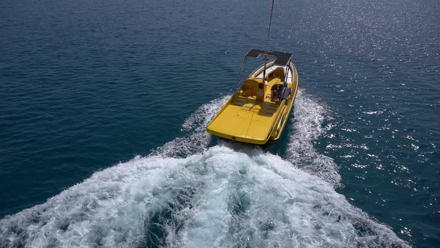 POV shot of parascending over blue sea. Launching from the yellow boat