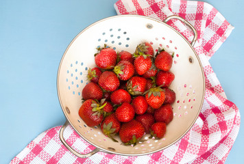 Fresh organic strawberries in a colander. Top view.