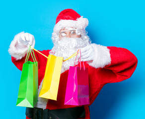 Funny Santa Claus have a fun with shopping bags on blue background