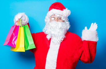 Funny Santa Claus have a fun with shopping bags on blue background