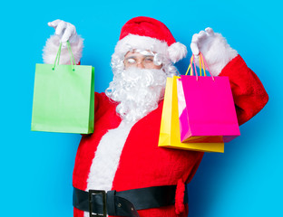 Funny Santa Claus have a fun with shopping bags on blue background