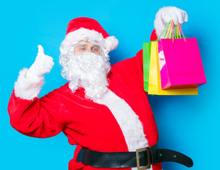 Funny Santa Claus have a fun with shopping bags on blue background