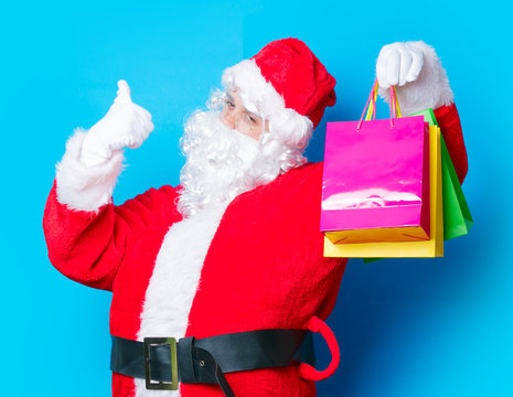 Funny Santa Claus have a fun with shopping bags on blue background