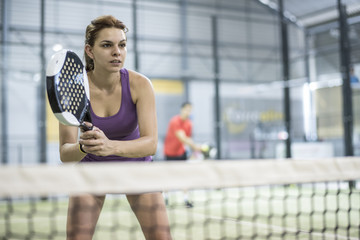 Couple playing paddle tennis in court with racket and balls