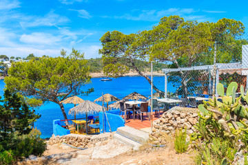 View of small coastal restaurant on cliff in Cala Portinatx bay, Ibiza island, Spain.