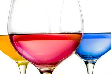 Yellow, red and blue liquid in wine glasses