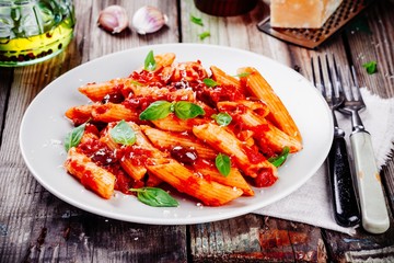 Italian penne pasta with tomato sauce, olives and basil