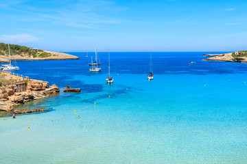 Sailing boats on blue sea in Cala Portinatx bay, Ibiza island, Spain