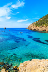 View of Cala Benirras bay with fishing boat on azure blue sea water, Ibiza island, Spain