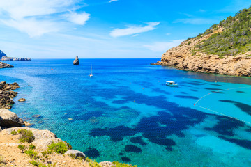 Fototapeta na wymiar View of Cala Benirras bay with fishing boat on azure blue sea water, Ibiza island, Spain