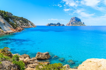 View of Cala d'Hort bay with beautiful azure blue sea water and Es Vedra island in distance, Ibiza island, Spain