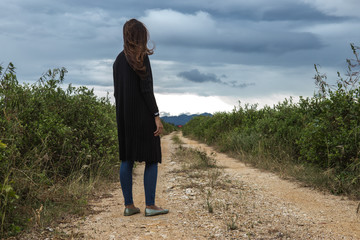 Women wearing  black dresses standing on the dirt road.