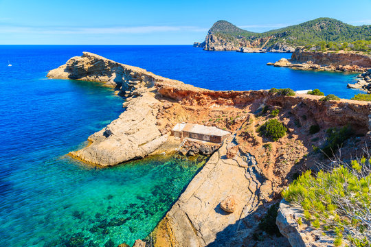 Boat houses at Punta Galera bay surrounded by amazing stone formations, Ibiza island, Spain