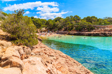 View of beautiful Cala Gracioneta beach with people swimming and sunbathing, Ibiza island, Spain