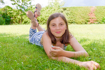 Naklejka na ściany i meble Beautiful pre teenage girl laying in grass